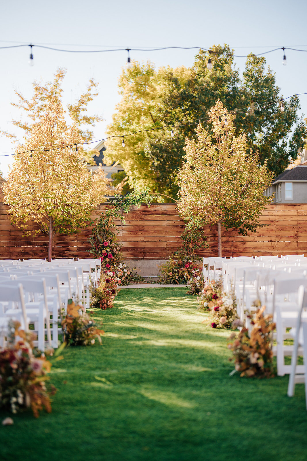 Ceremony set up with bright colored florals and white chairs. Wedding ceremony in Longmont Colorado