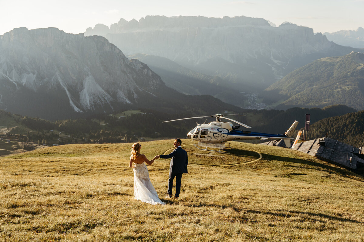 Bride and groom boarding helicopter with mountain views in the Dolomites