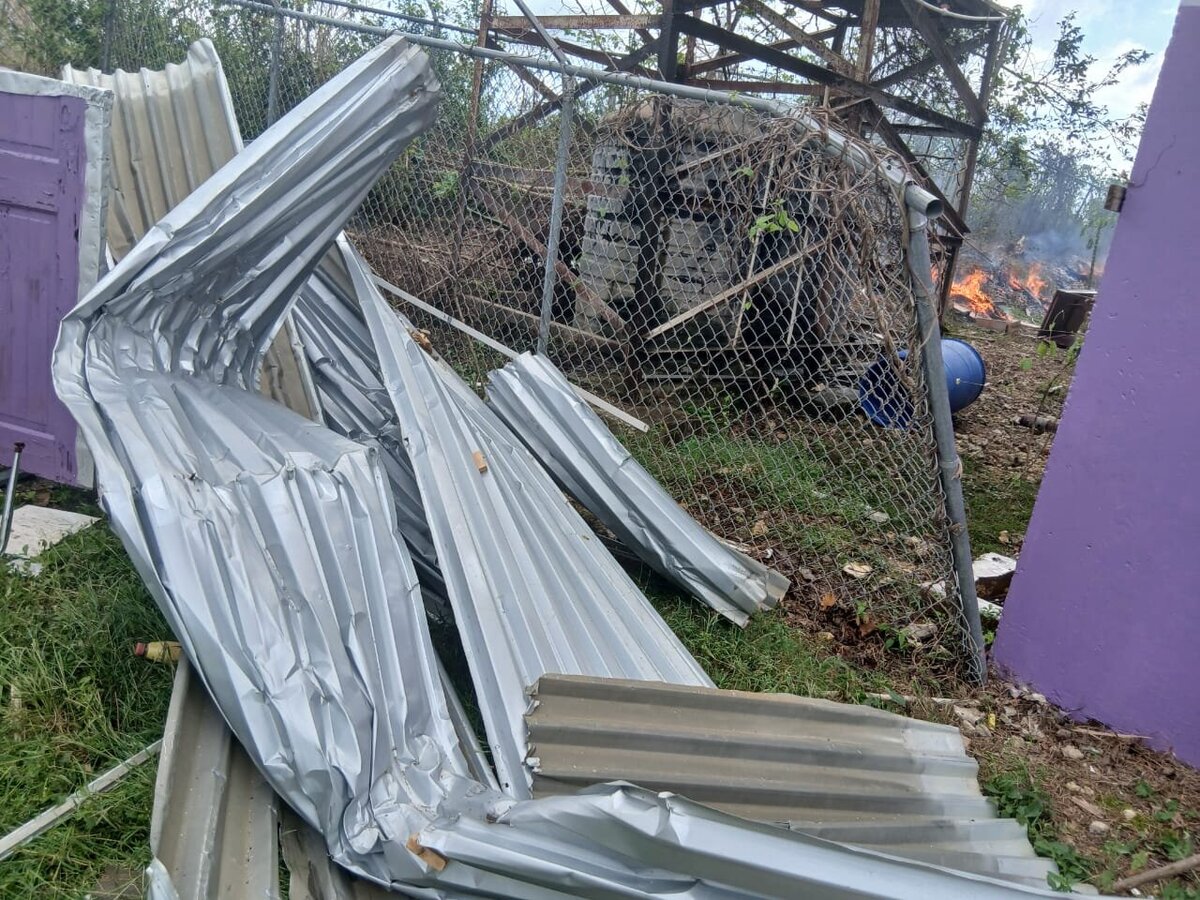 Twisted metal roofing panels scattered on the ground outside the school following Hurricane Melissa.