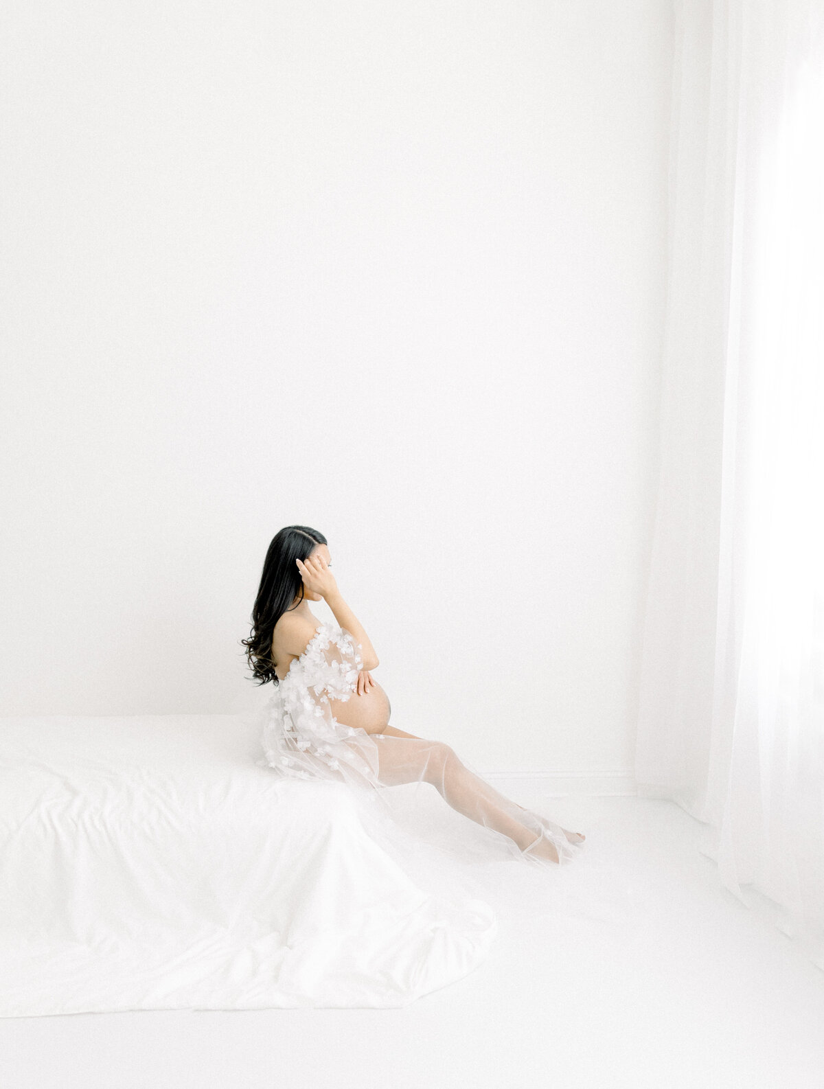 Expecting mother dressed in a beautiful tulle gown holding her belly