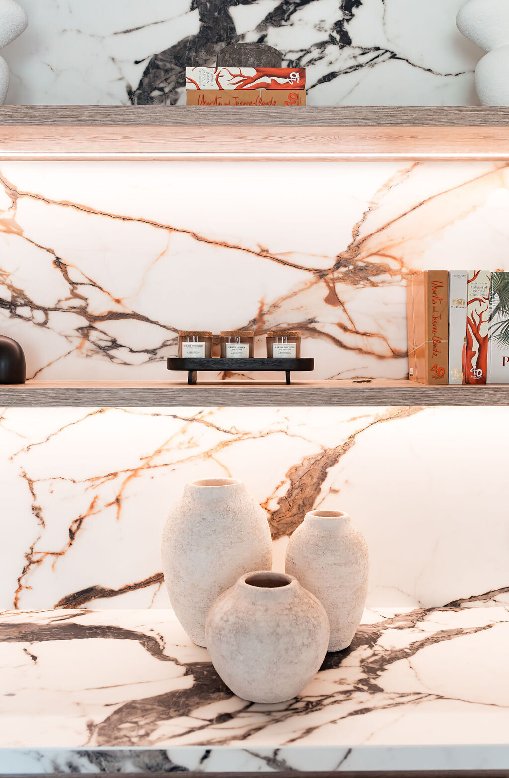 A marble bar with built-in shelving, integrated lighting emitting a soft glow, and chic decor.