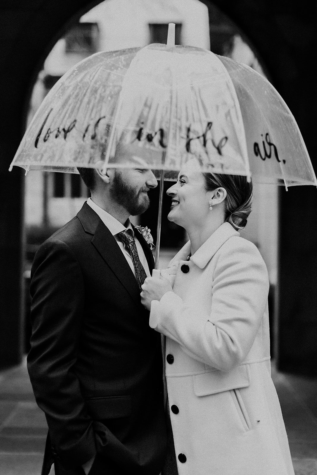 Just Married photo session couple in an old Chicago church couple stands in rain under umbrella that reads love is in the air.