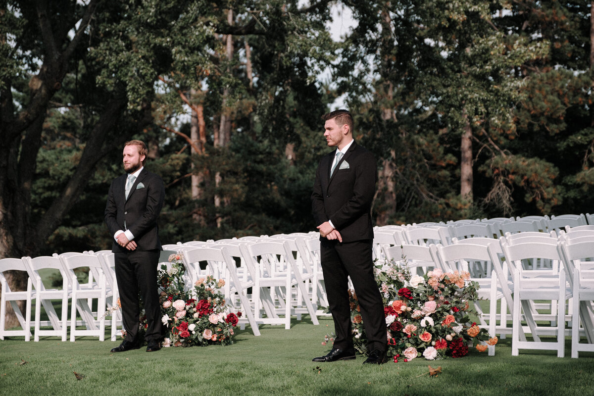 groomsmen stand in from of ceremony space ready to welcome guests
