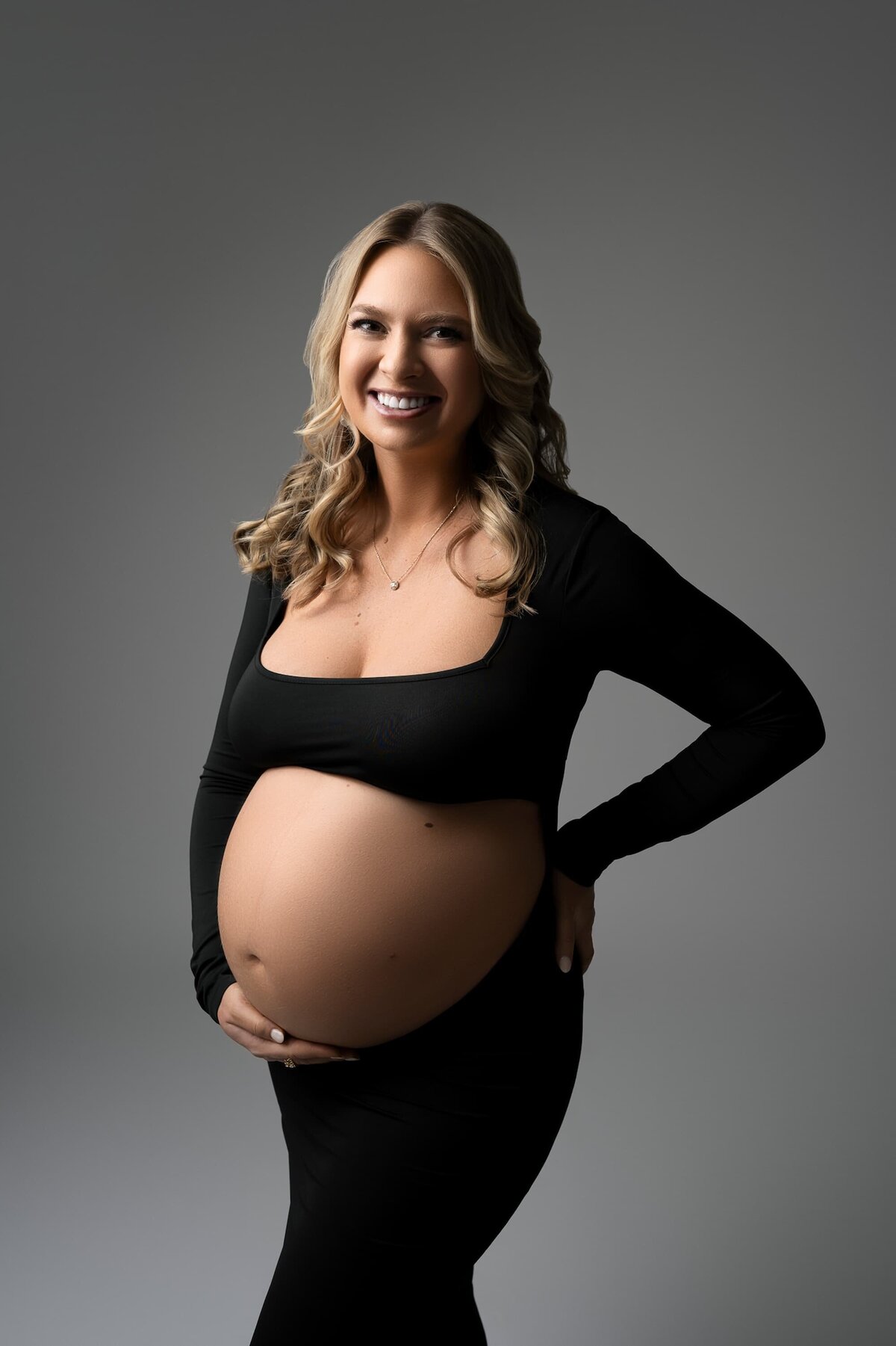 pregnant woman blonde hair black fitted belly cutout dress