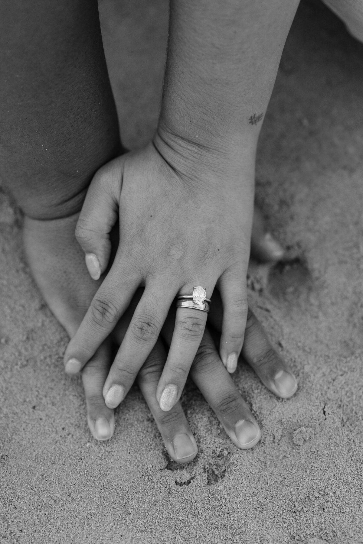 Oahu Hawaii Elopement couple at Secret Island Beach with wedding rings hands in sand in black and white color.