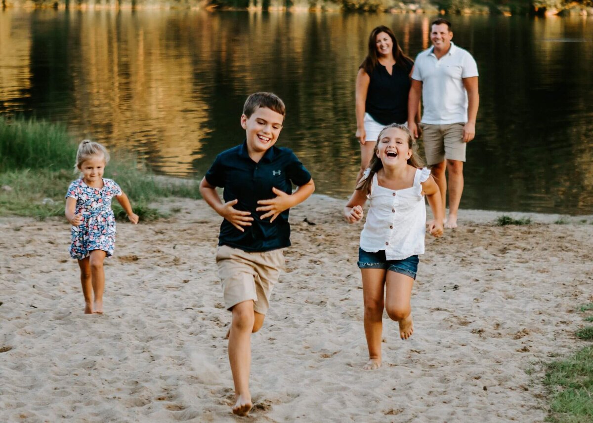 A Pittsburgh family is running on the sand near a lake.