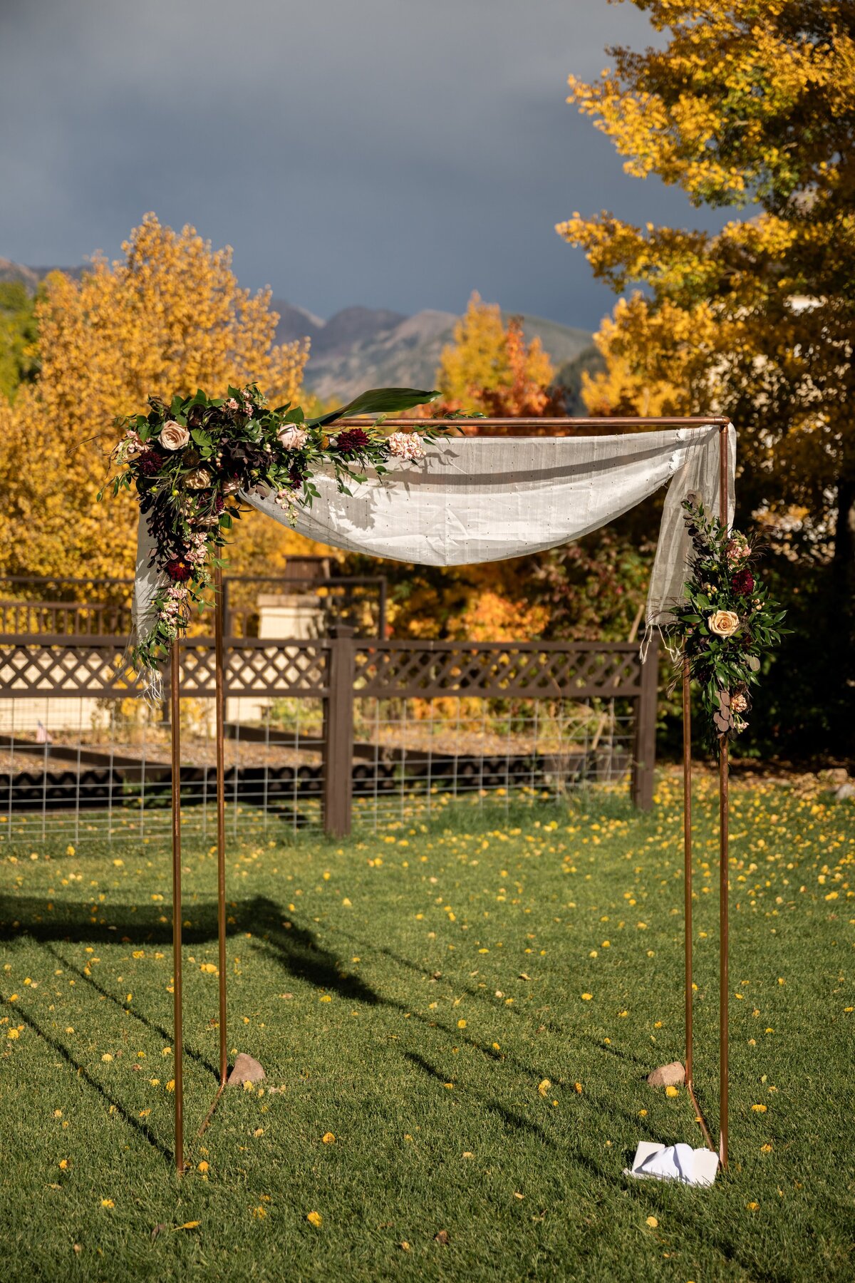 Copper Chuppah with peach and burgundy flowers.