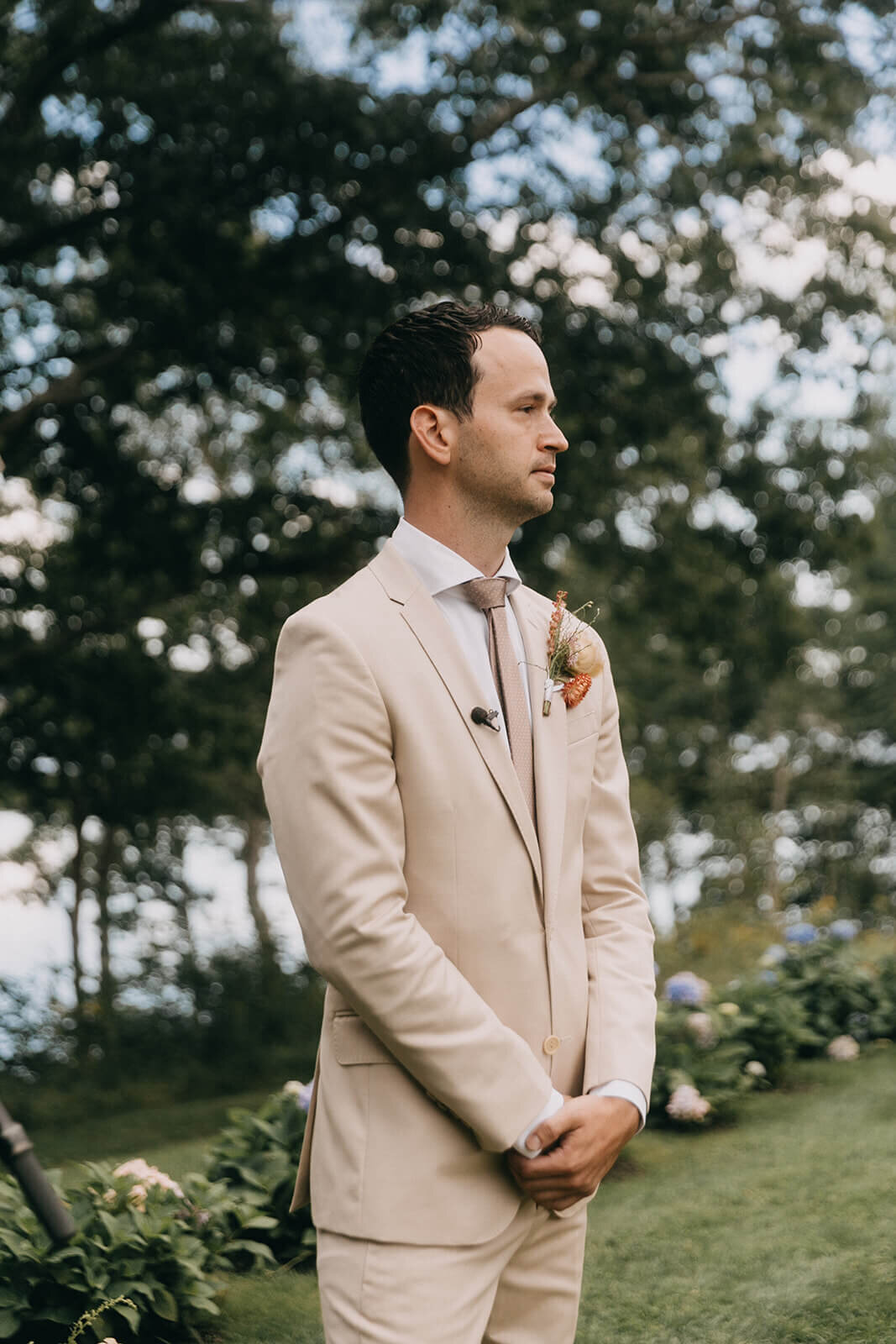 25.groom-waiting-ceremony-beige-suit-natural-green-background