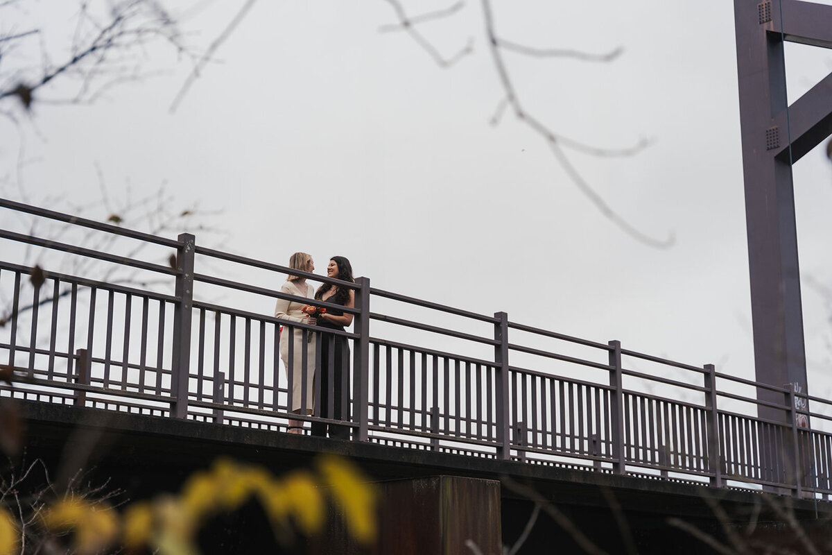 Landscape view of the newlywed women standing on a Nashville bridge 