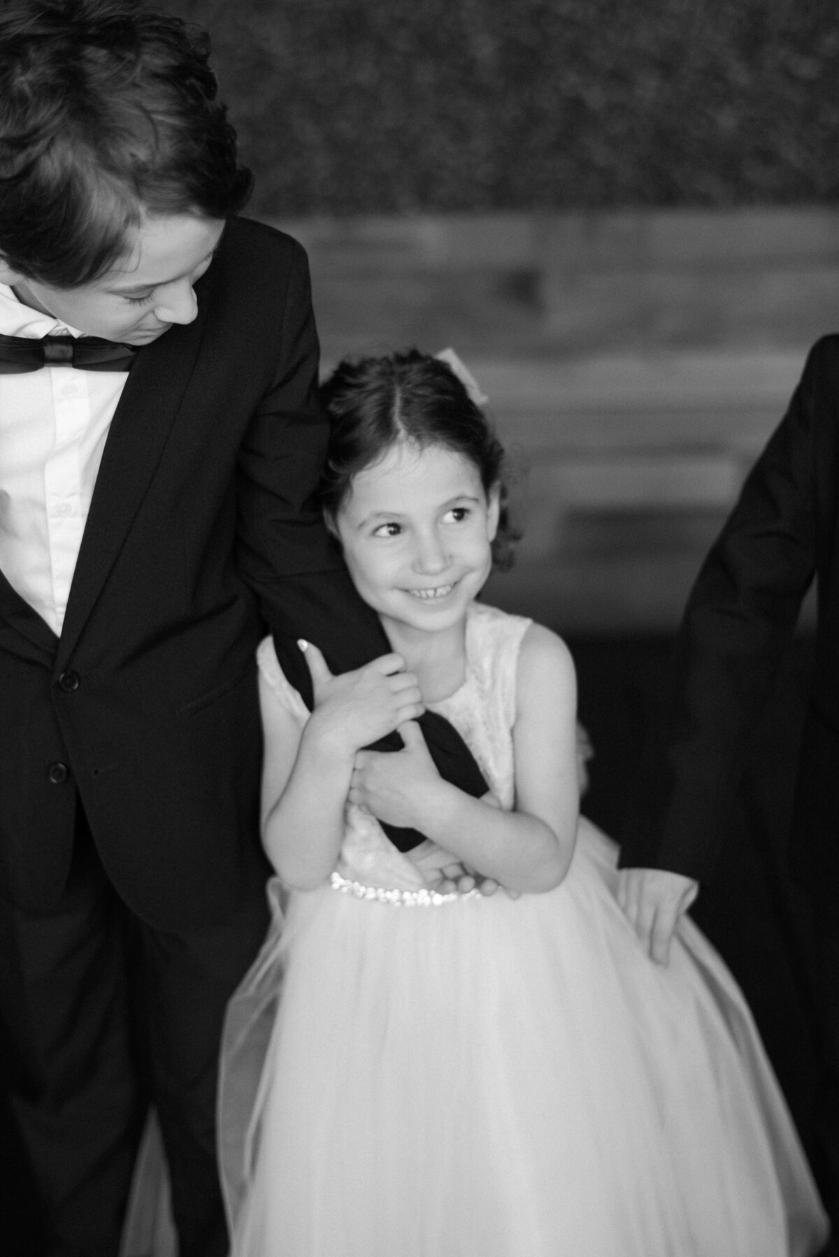 Flower girl holds the arm of the ring bearer as they walk down the aisle 