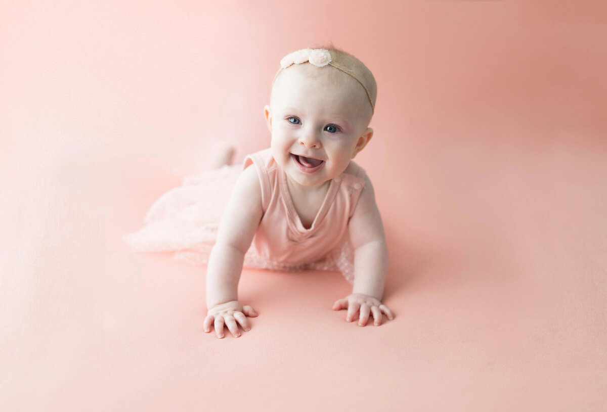 Crawling baby girl in pink tutu dress on pink background - sitter session Maple Grove milestone photographer