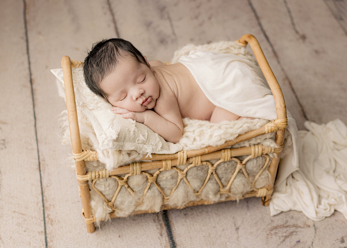 baby in bamboo bed laying on white pillow