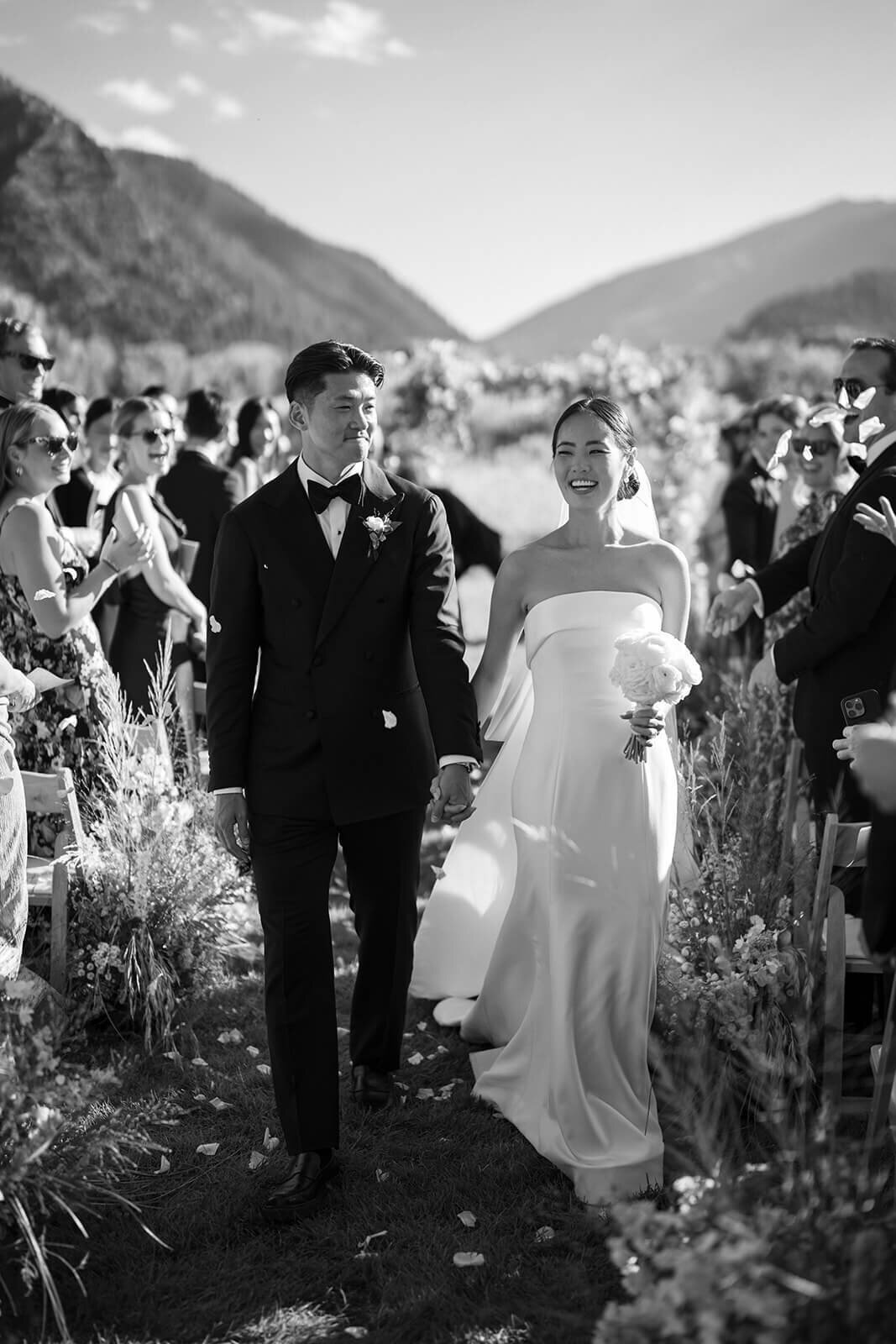 Bride and Groom walk down the aisle among cheering guests during the recessional of their Aspen Meadows Resort wedding.