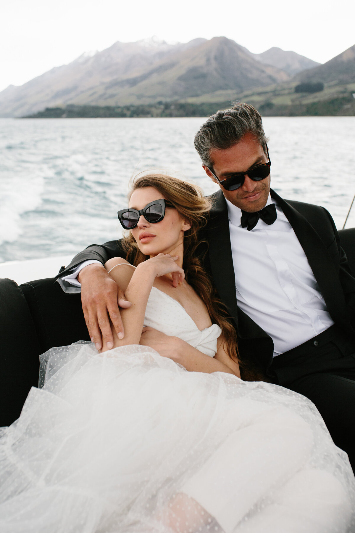 The Lovers Elopement Co - wedding photography - bride and groom embrace on boat on Queenstown lake