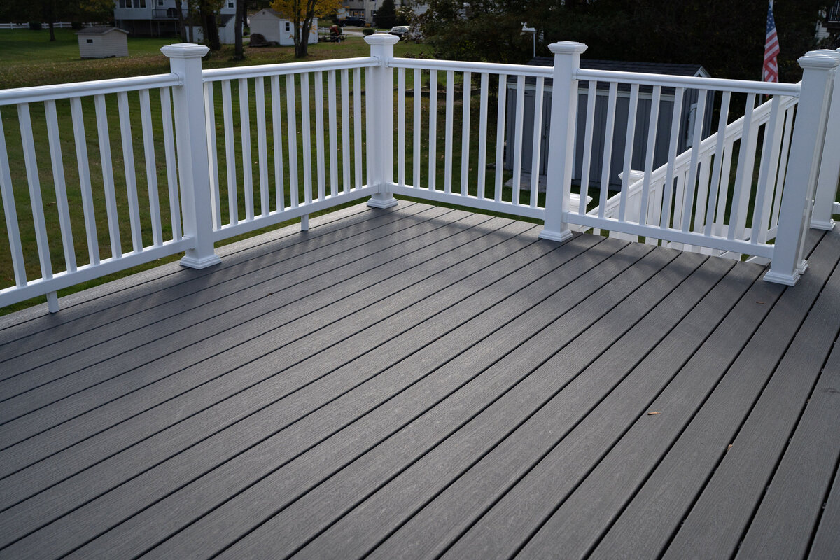 A finished grey composite deck with white PVC hand rails