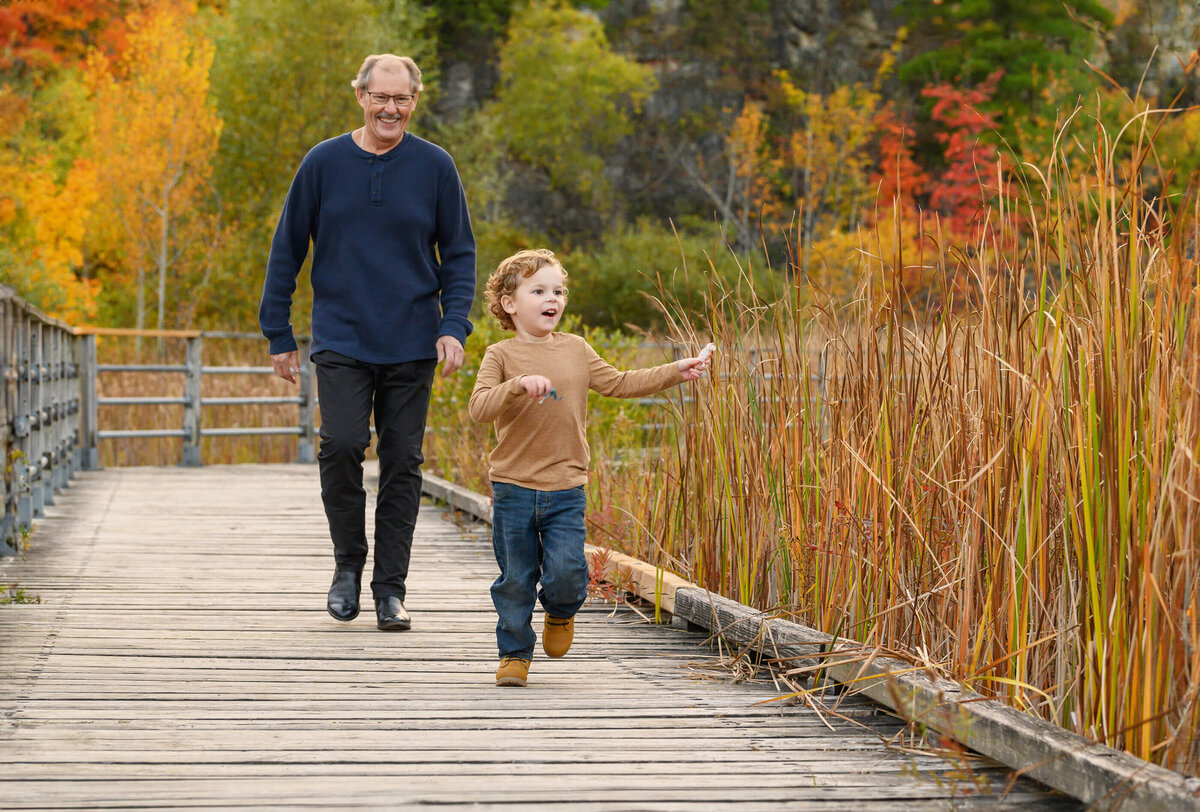 grandpa and grandson running on a bridge for their extended family fall photos in Burlington, ON