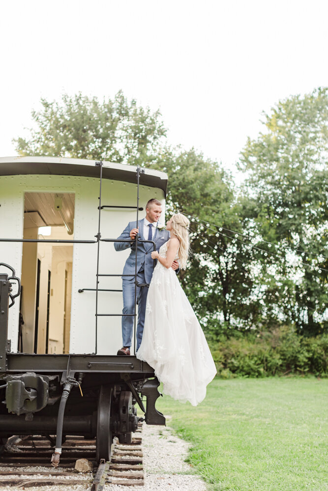 bride and groom gazing at each other while standing on a train
