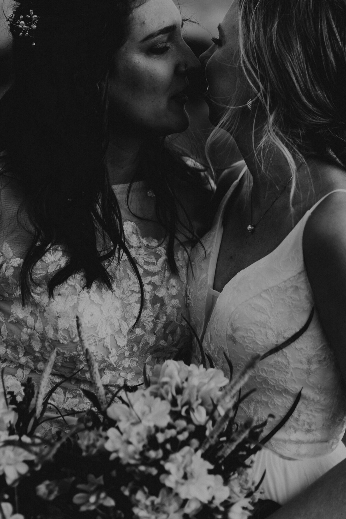 Two newlywed brides holding each other about to kiss