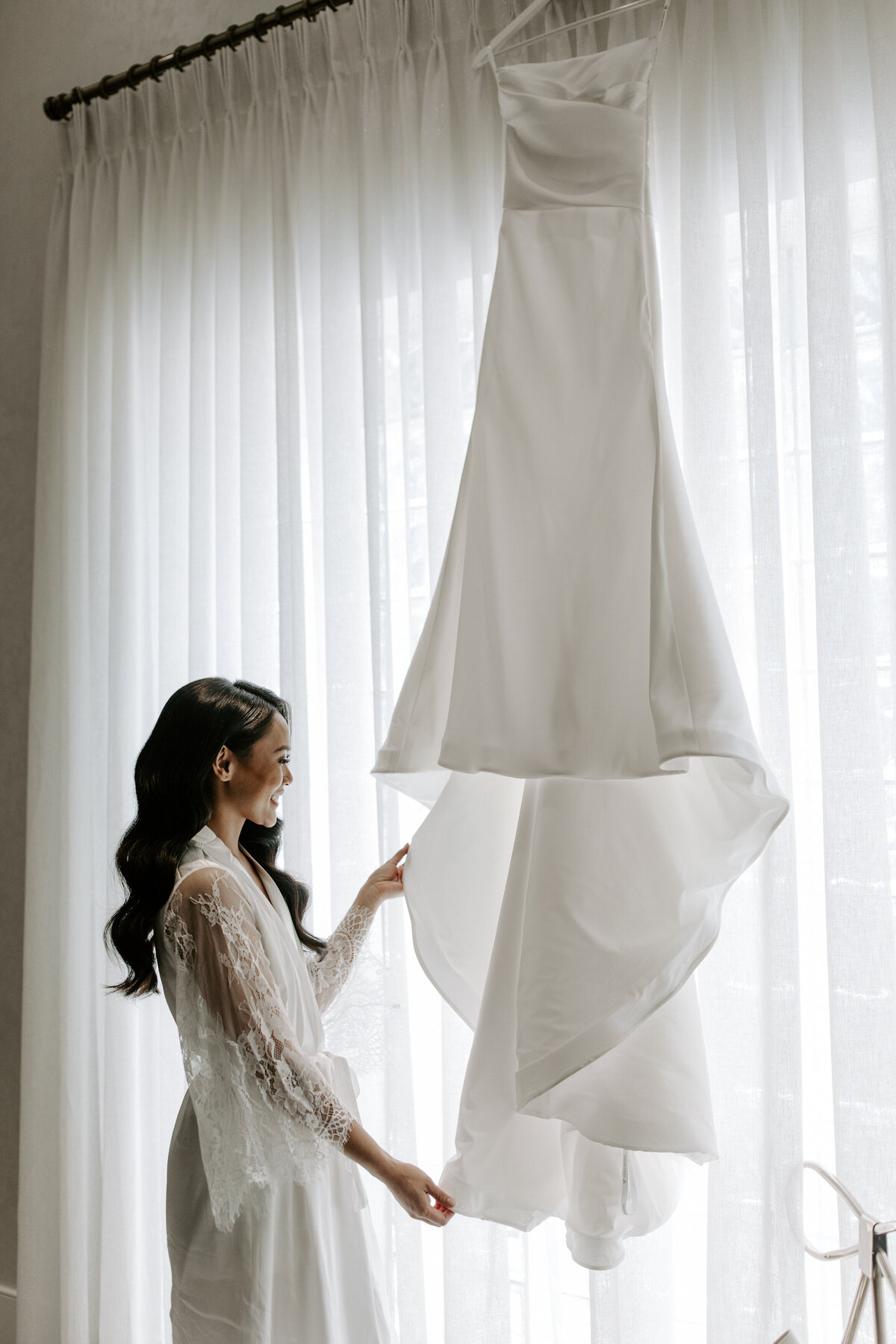 A bride admires her dress near the window at The Stirling Club.