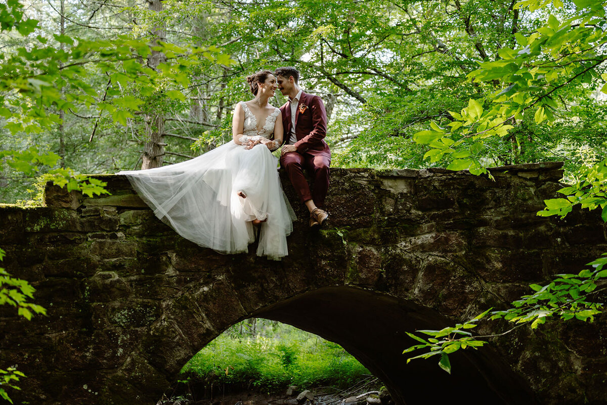 Newlywed sitting on top of a stone bridge
