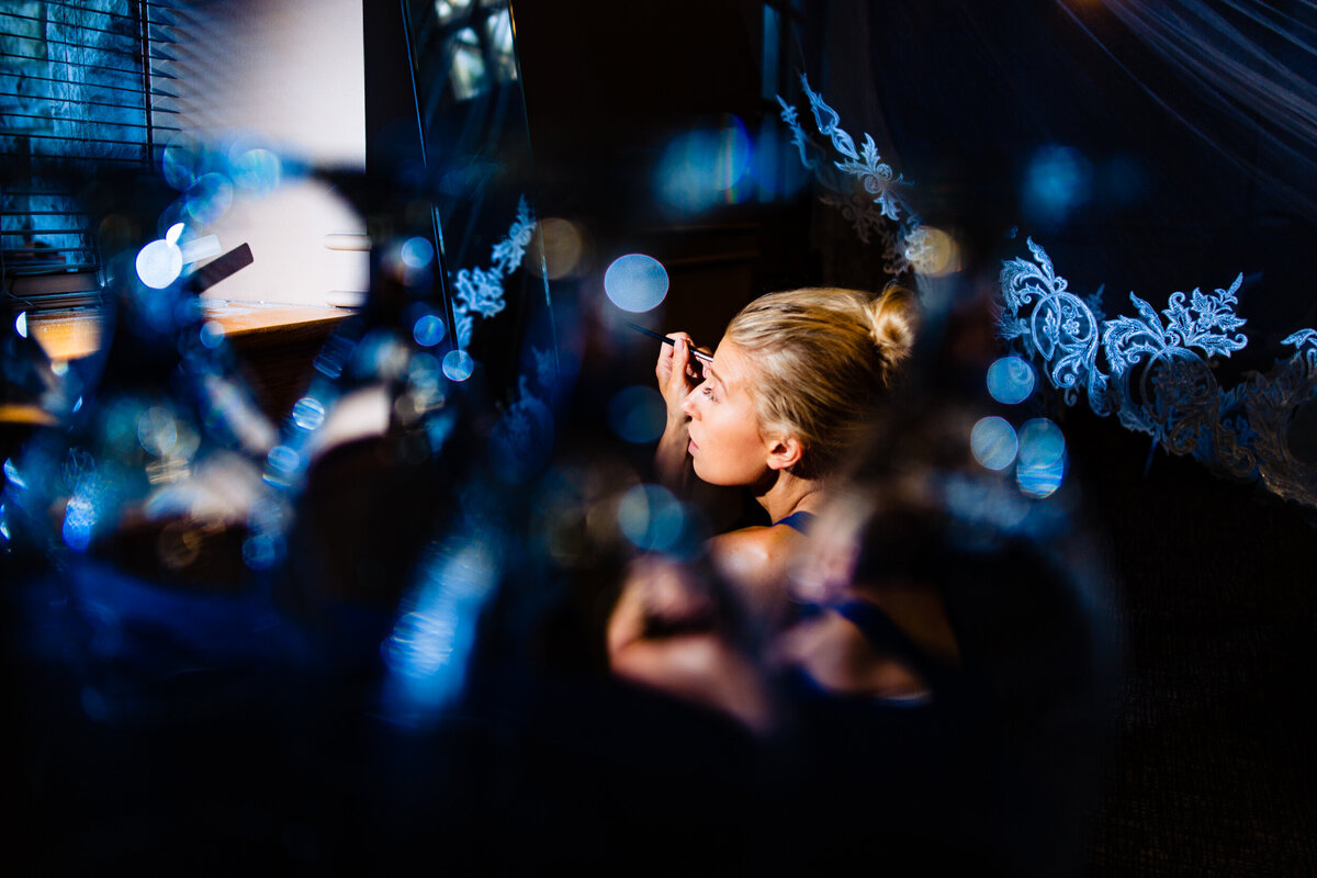 One of the top wedding photos of 2020. Taken by Adore Wedding Photography- Toledo, Ohio Wedding Photographers. This photo is of a bride appling her makeup in the morning before the wedding ceremony