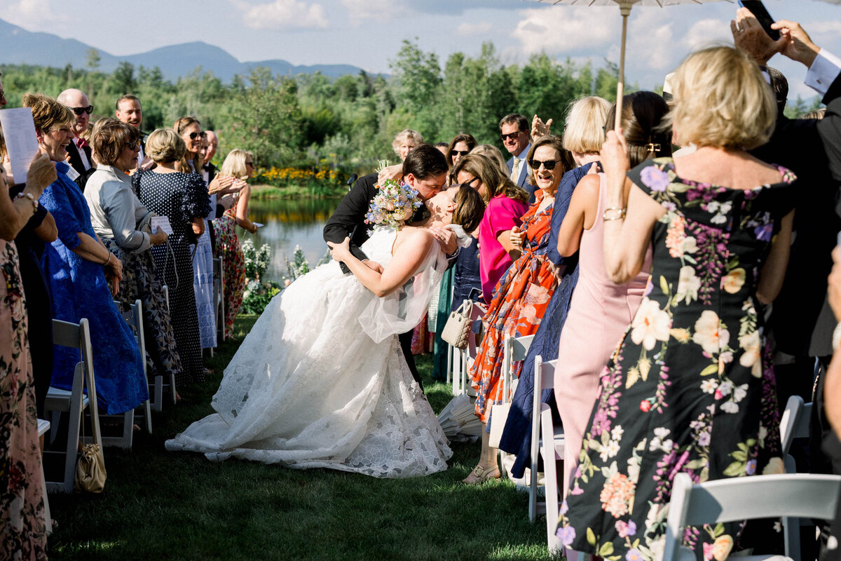 bride and groom kissing in ceremony aisle