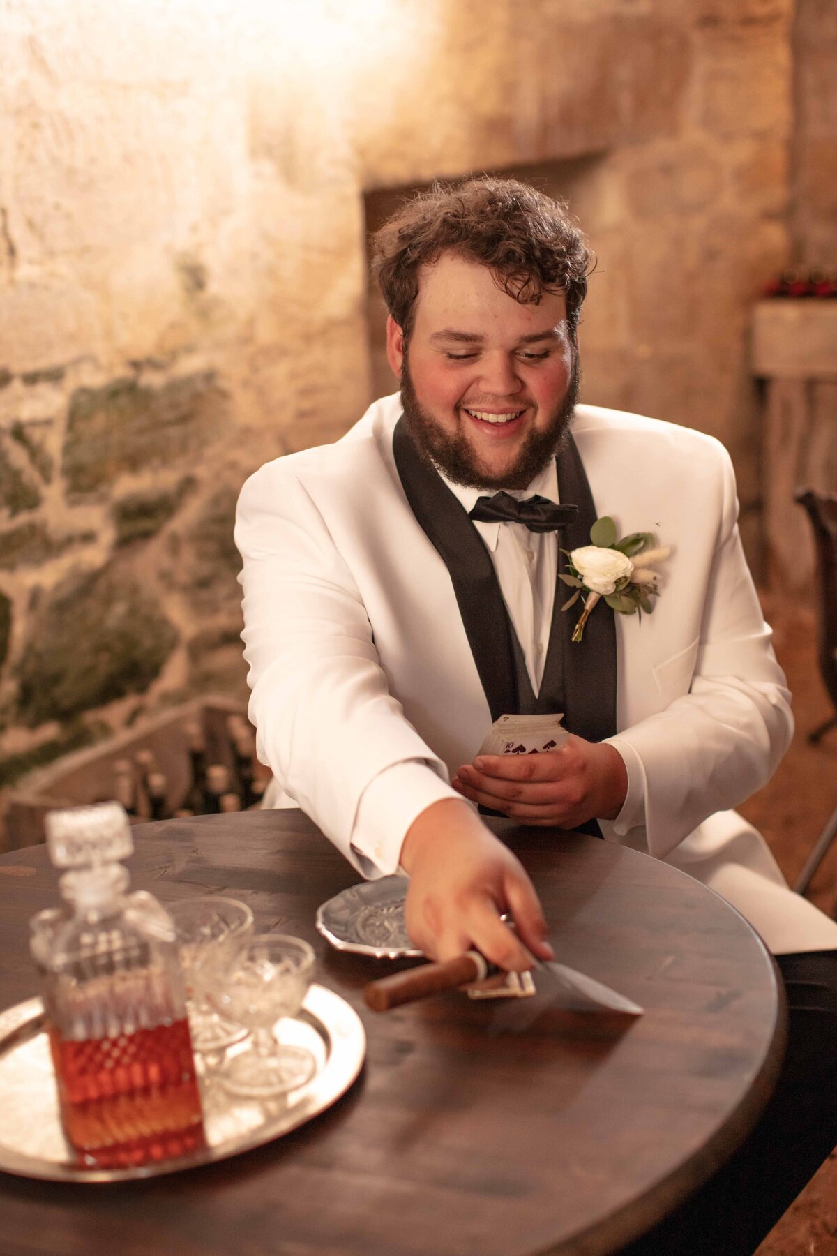 white tuxedo playing cards  whiskey cigar in cellar 1850 settlement a hill country wedding venue in Bulverde by San Antonio wedding photographer Firefly Photography