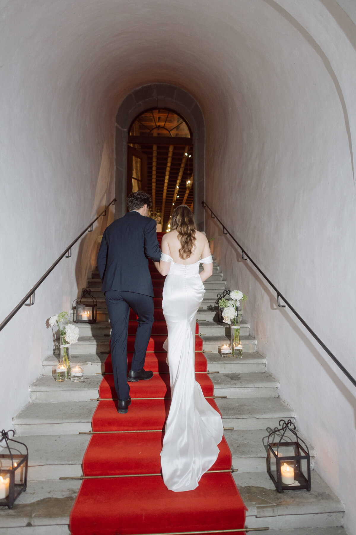 Brautpaar auf rotem Teppich beim Treppenaufgang – Hochzeit im Palast Hohenems mit festlichem Ausklang.
