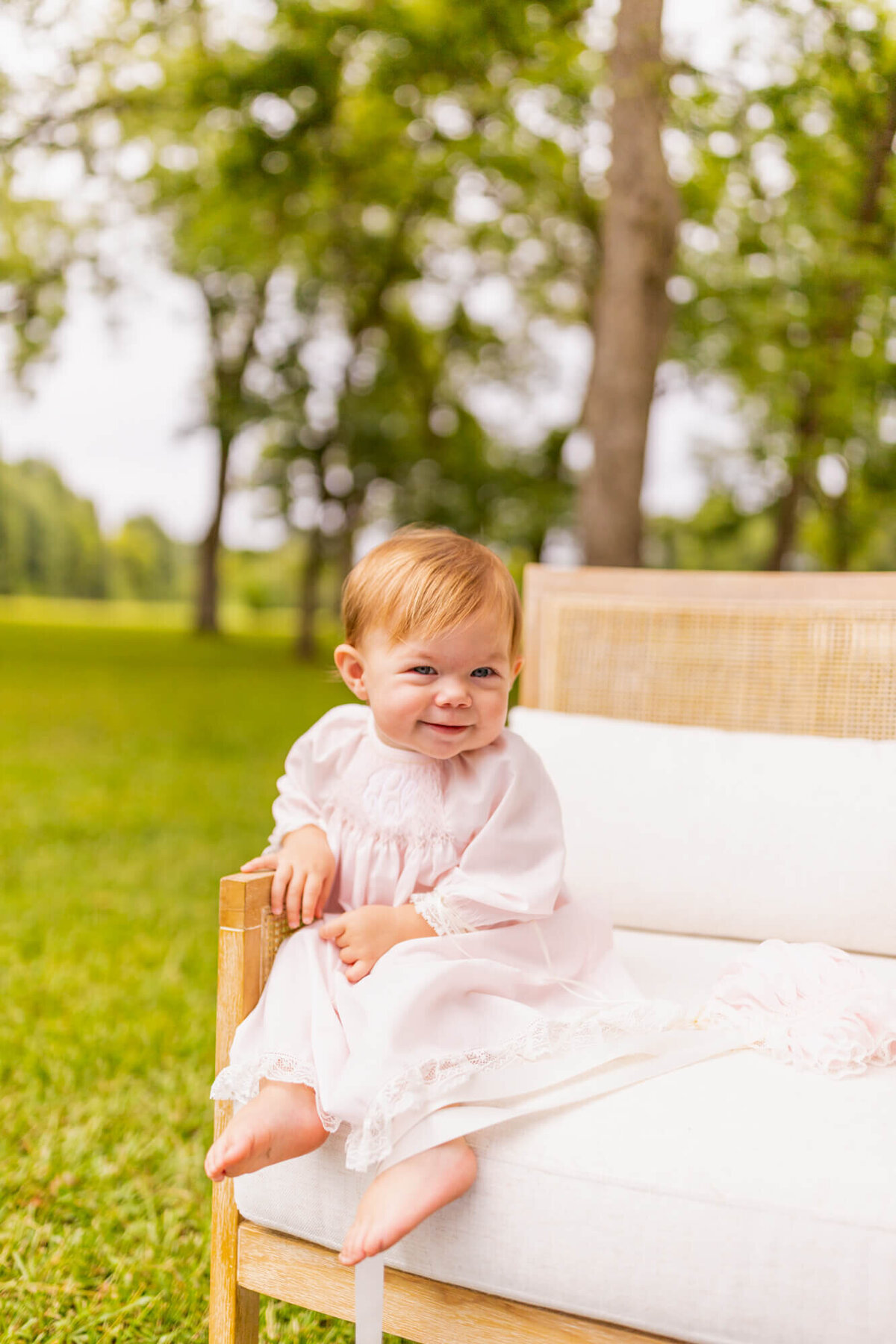 toddler girl sitting in a chair in a field wearing a pink dress