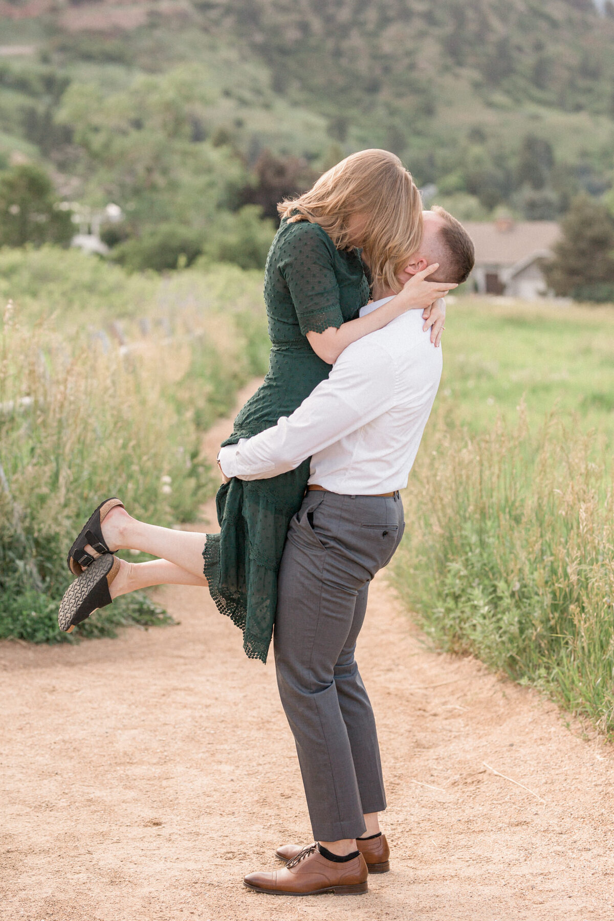 A man lifts up his new fiancee while she kisses him