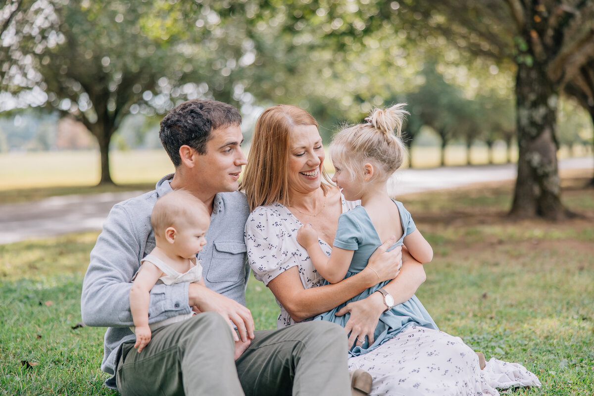 family of four sitting under trees