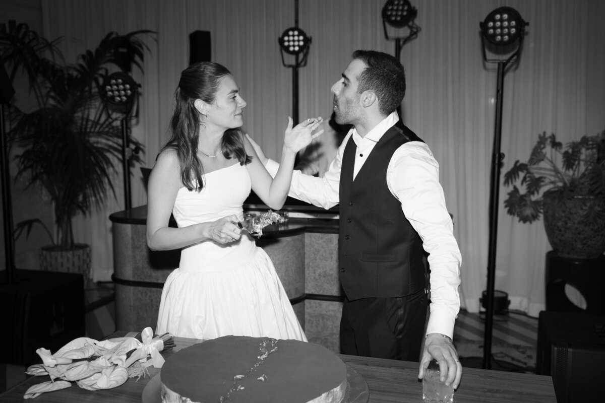 Bride and groom laughing together during cake cutting moment

