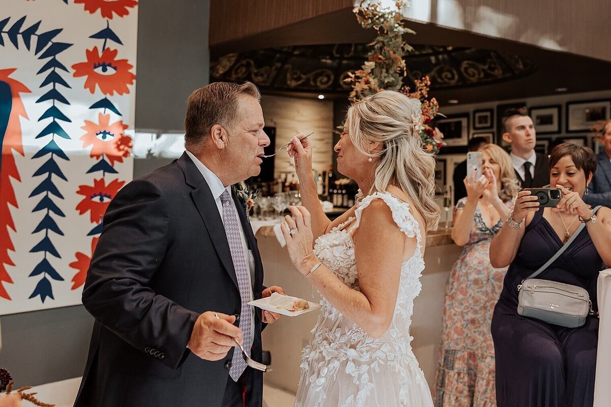 bride and groom having their first cake bite feeding each other