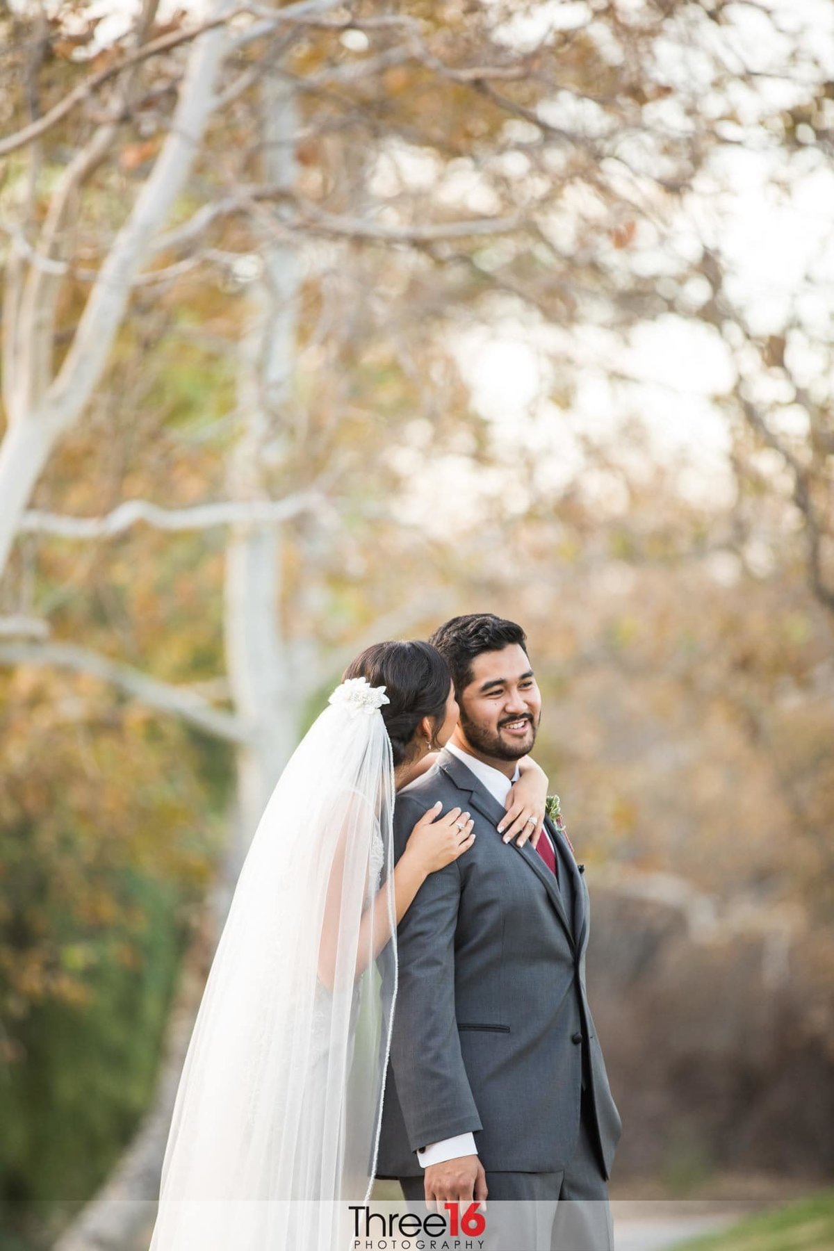 Bride embraces her Groom from behind and whispers in his ear