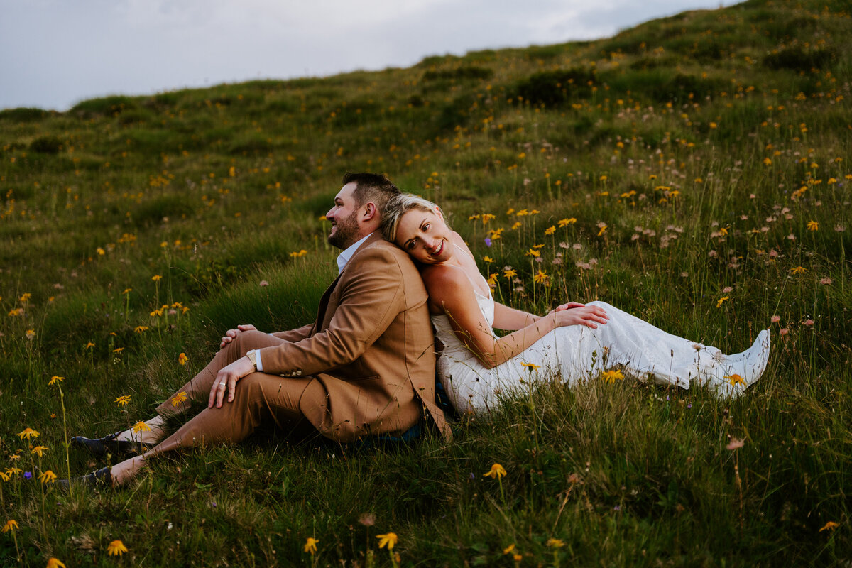Couple sitting together on grassy hill during Dolomites elopement