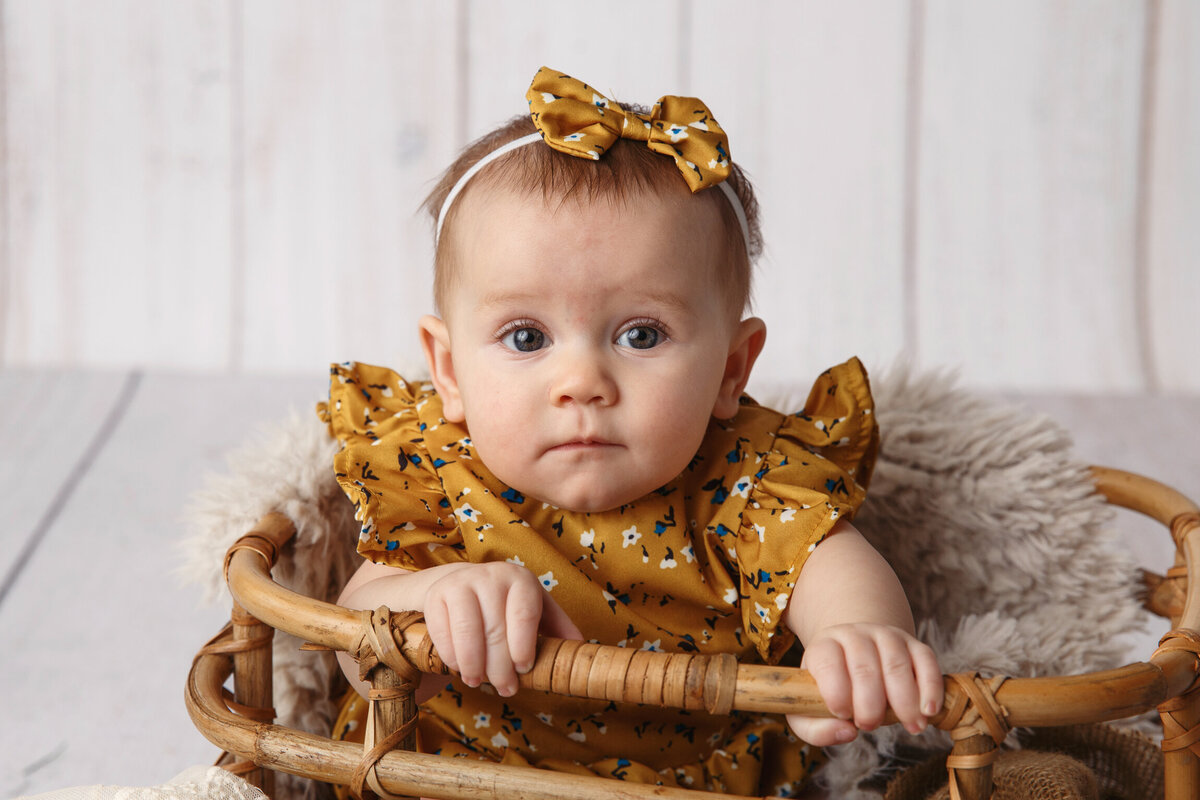 Closeup portrait of a six month old baby sitting in a wooden basket