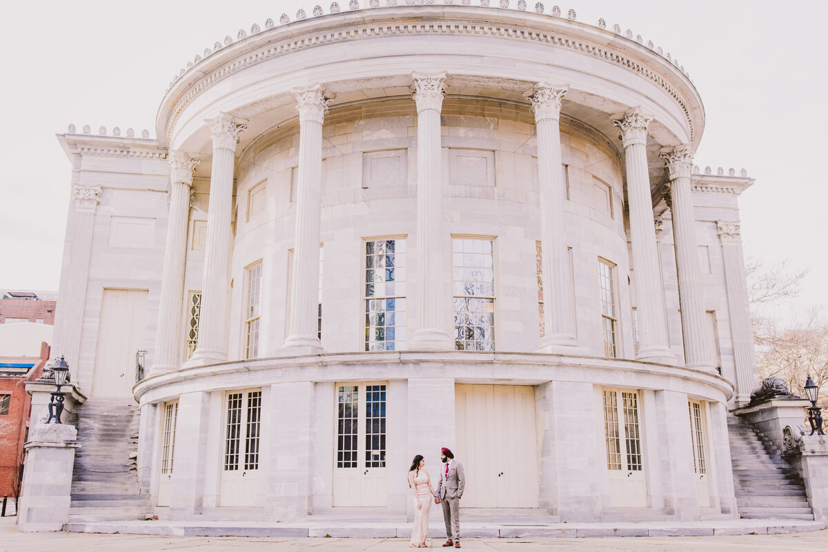 An engaged couple standing in front of the merchant exchange building in old city philadelphia