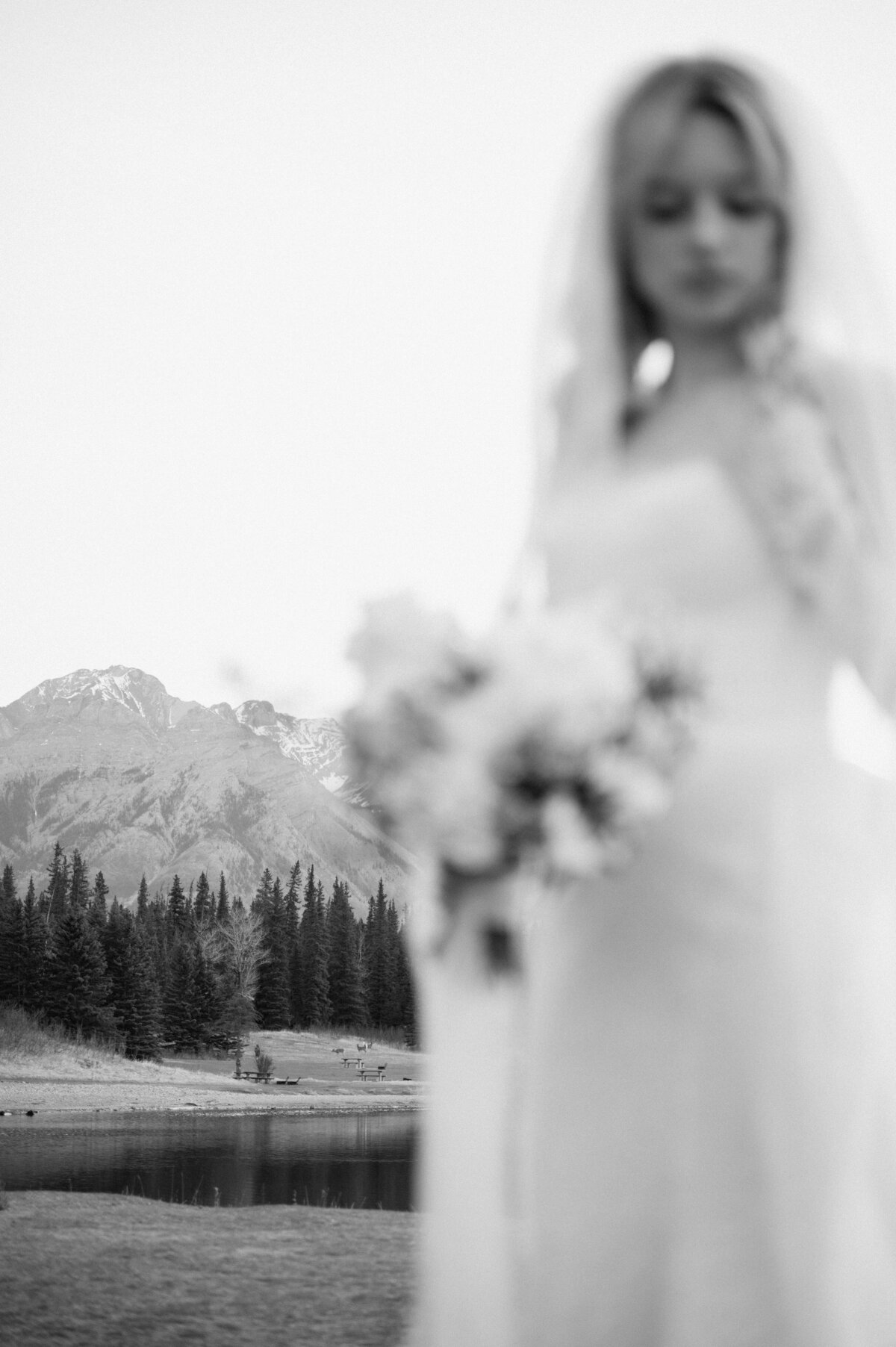 Creative bokeh portrait of bride with mountains softly blurred in the background.