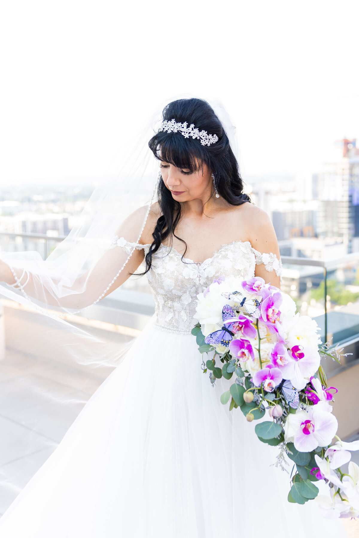 Bride holding colorful floral bouquet of orchids and white florals