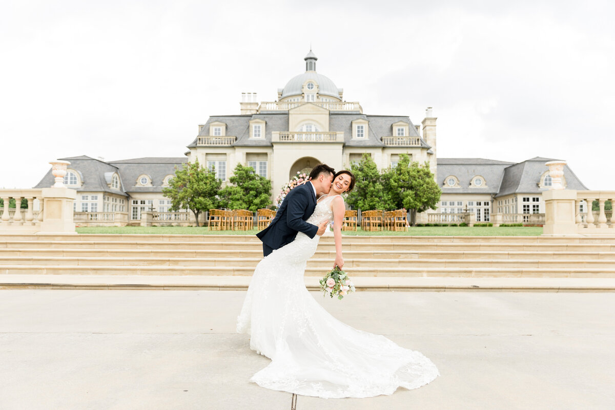 Bride and Groom dip pose in front of gorgeous luxury mansion in north Texas on wedding day