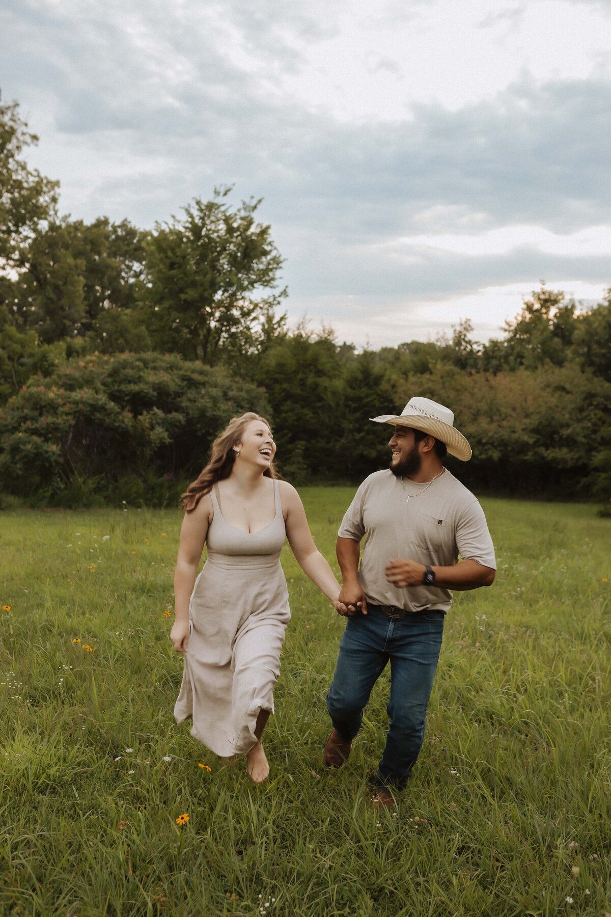 Couple running barefoot in Missouri field during spring