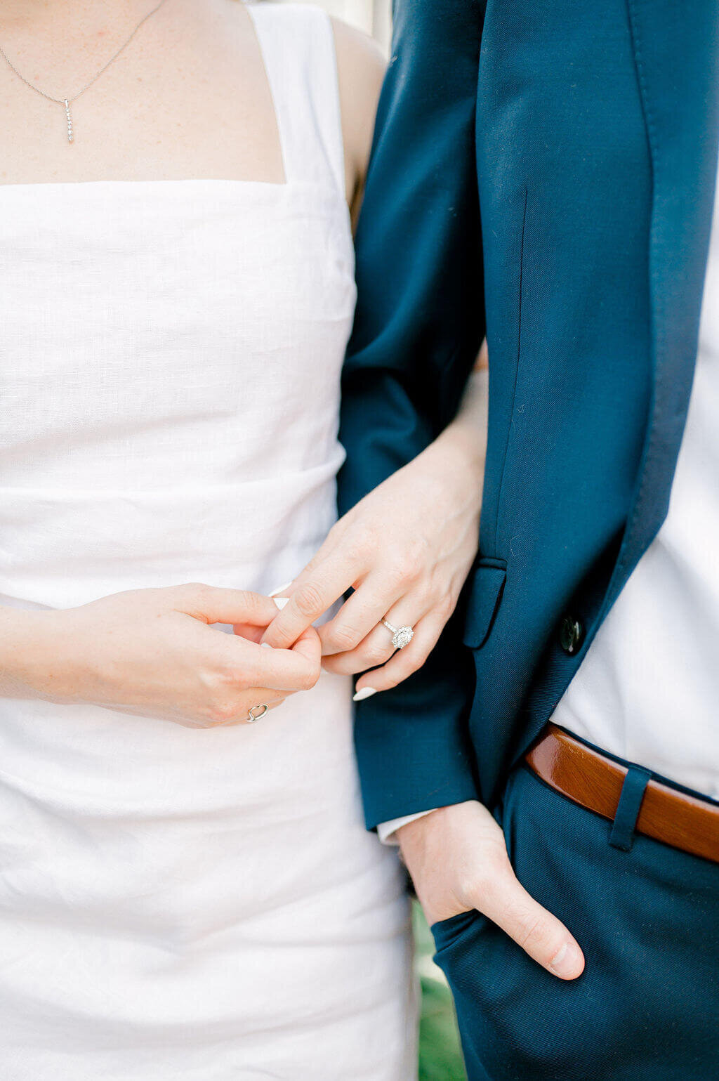 Simple image of a couple linking arms during their engagement shoot. Photo emphasizes an engagement ring