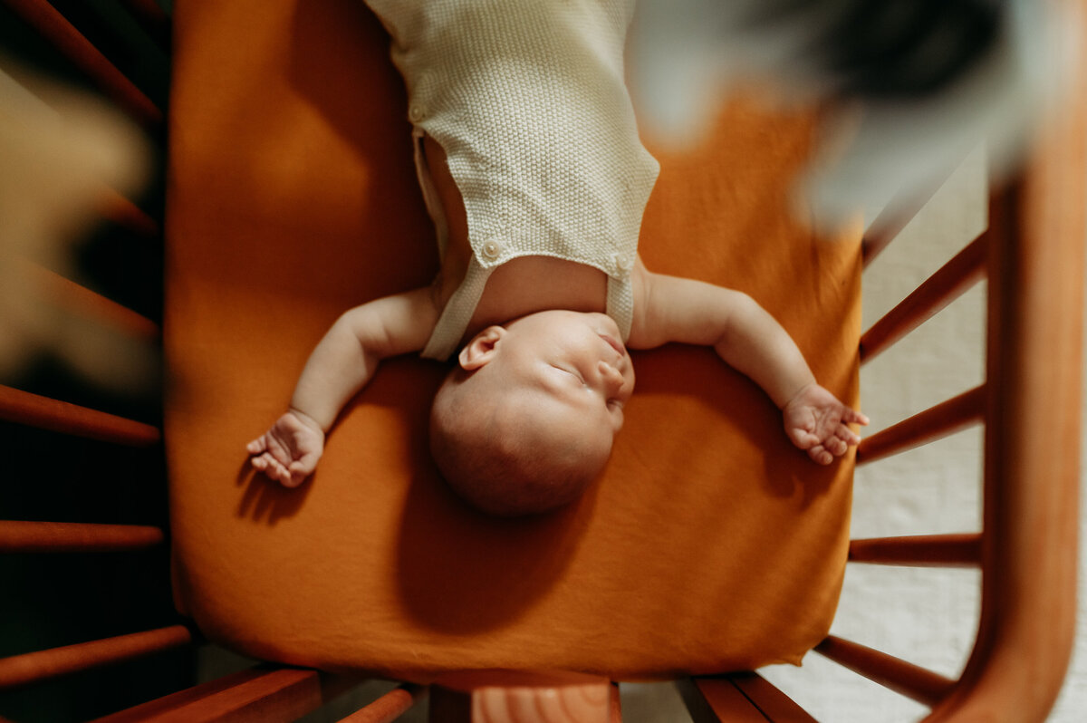 Overhead luxury image of a baby sleeping with arms wide, so perfect and cozy.