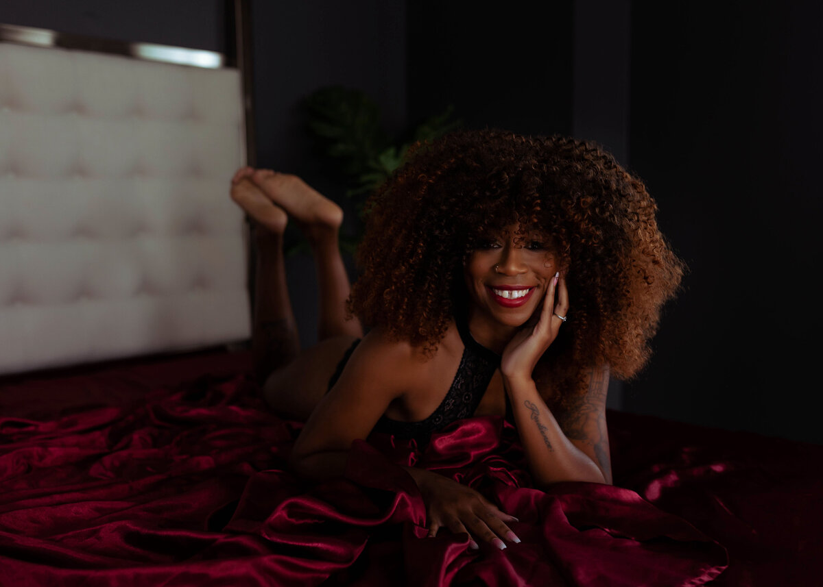 boudoir portrait of african american woman laughing on red sheets elkridge MD