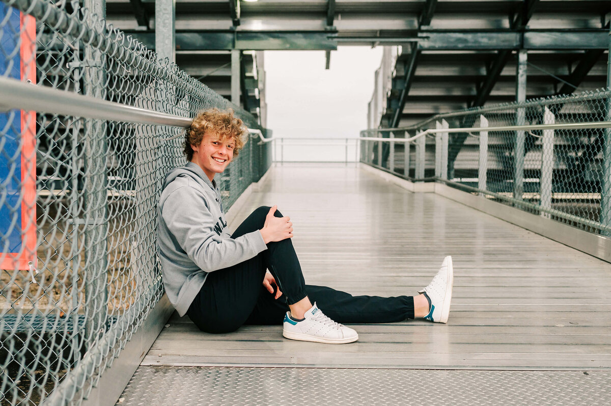 high school senior sitting on bleachers captured by Branson Missouri senior photographer Jessica Kennedy of The XO Photography