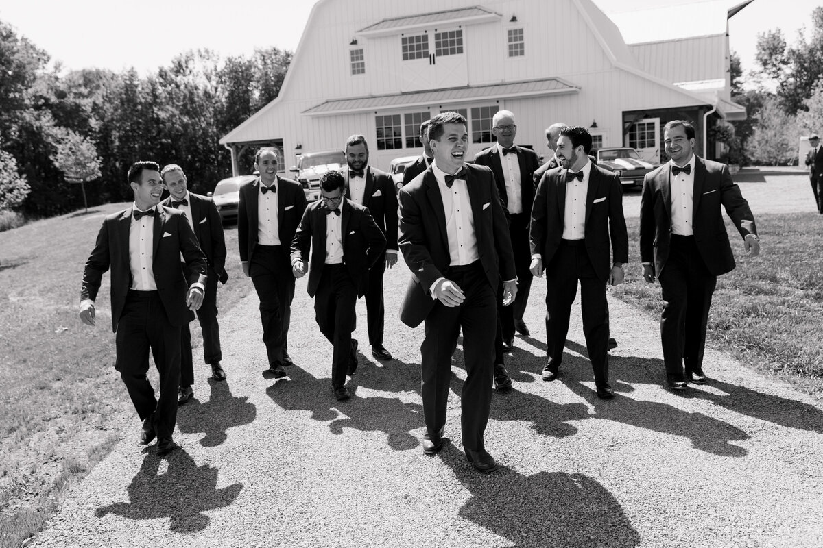 Black and white photo of a groom and groomsmen walking in front of the Wildflower On Watts venue