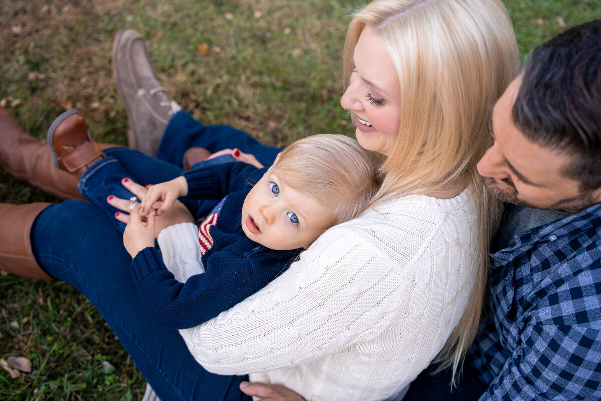 Baby blue eyed child leaning into moms chest looking up at camera