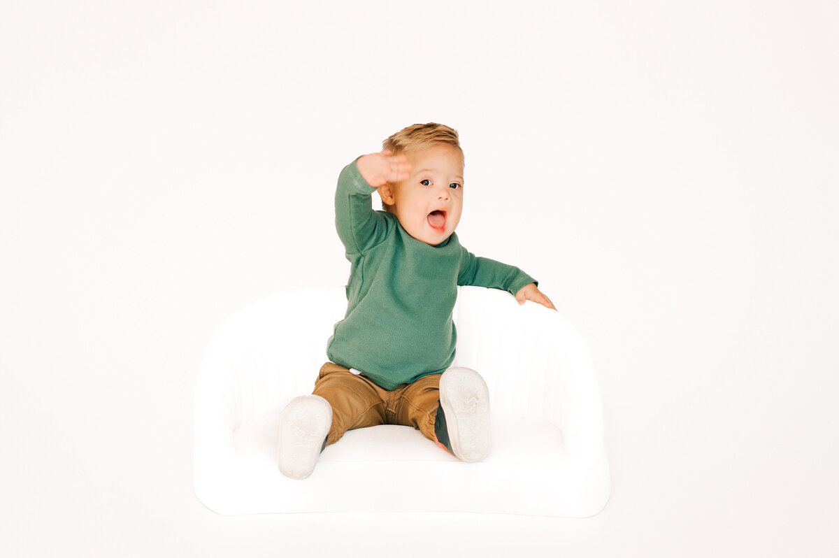 Springfield MO kids photographer captures baby boy sitting on couch waving