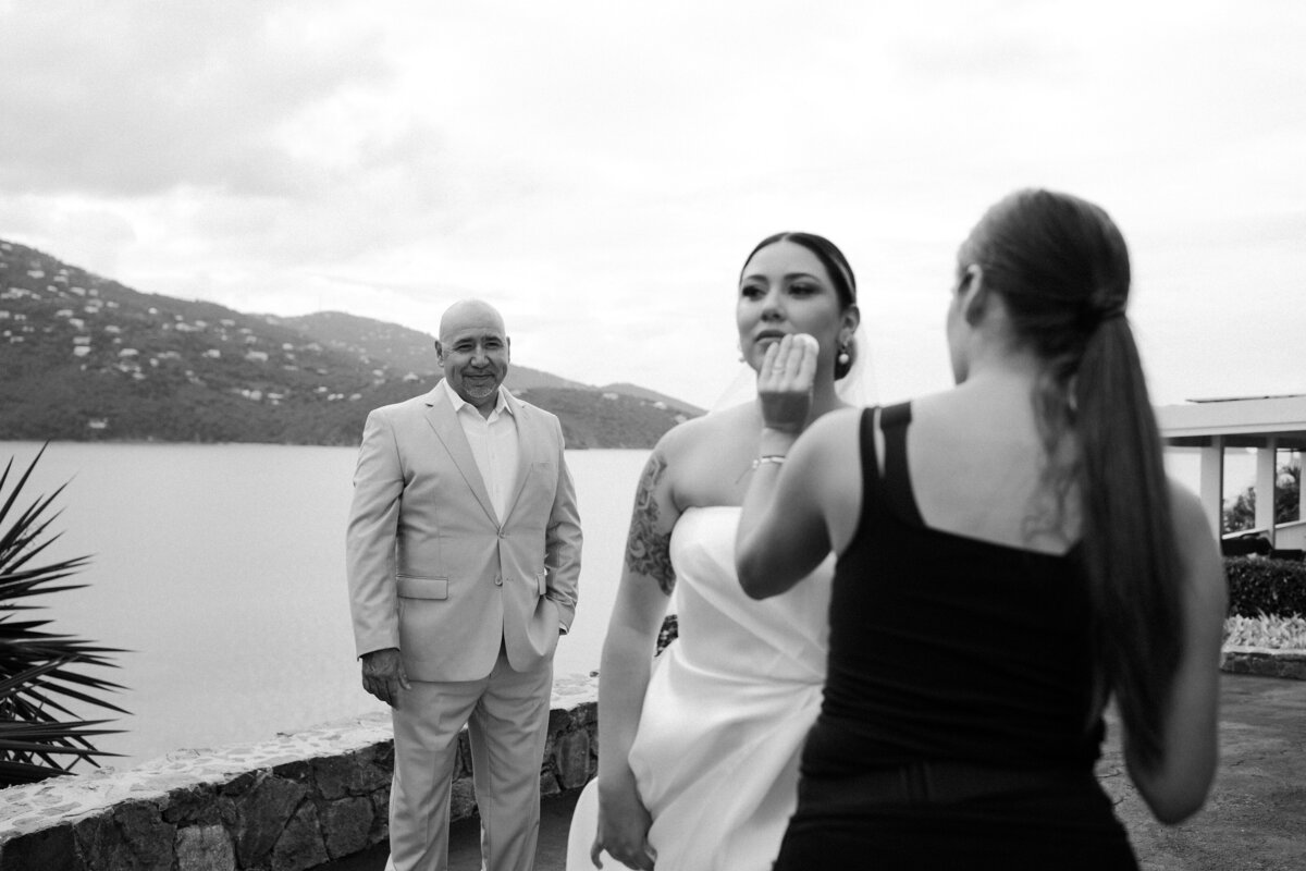 A woman fixing a brides makeup while a man stands behind them