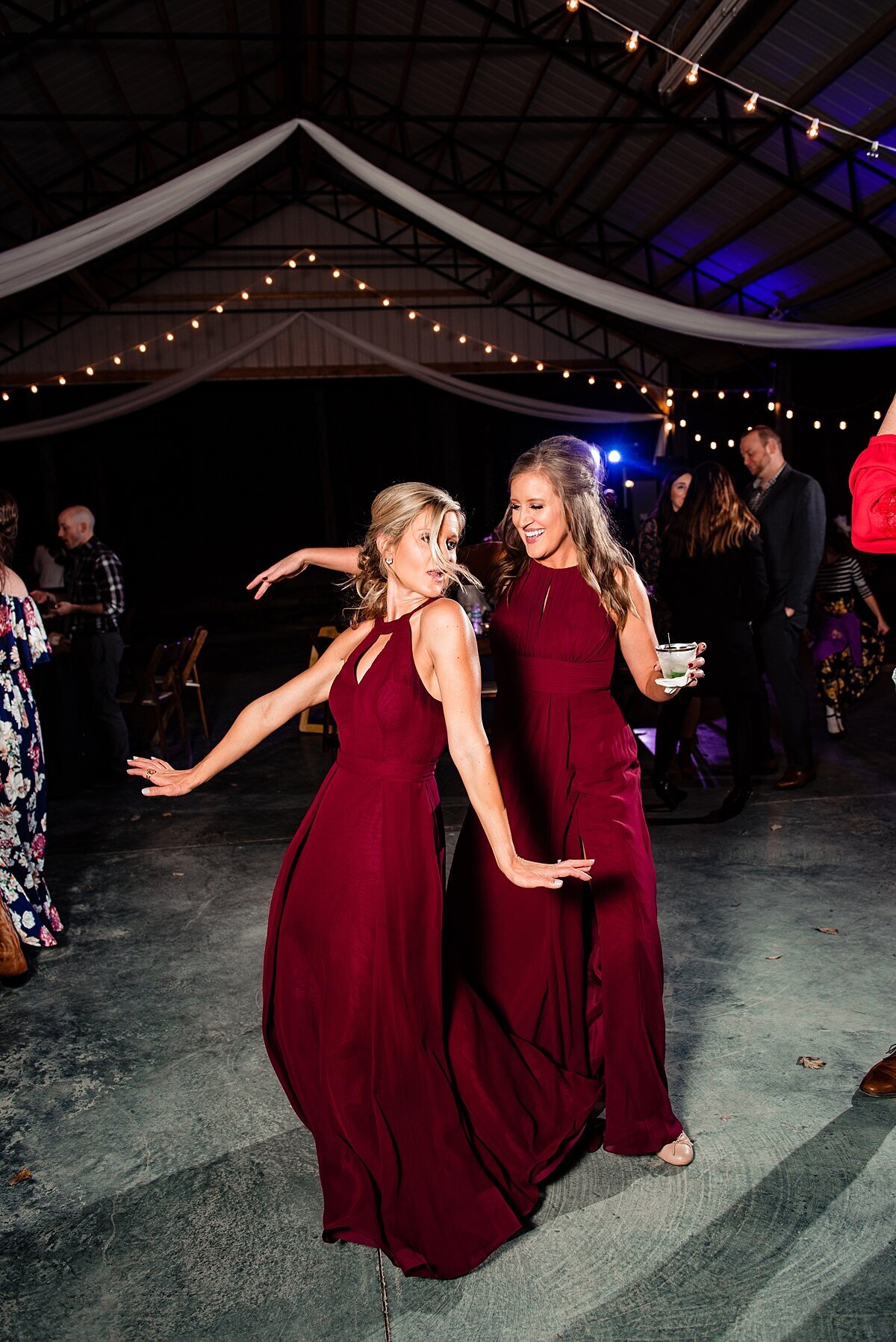 bridesmaids wearing dark red dresses dancing at outdoor reception